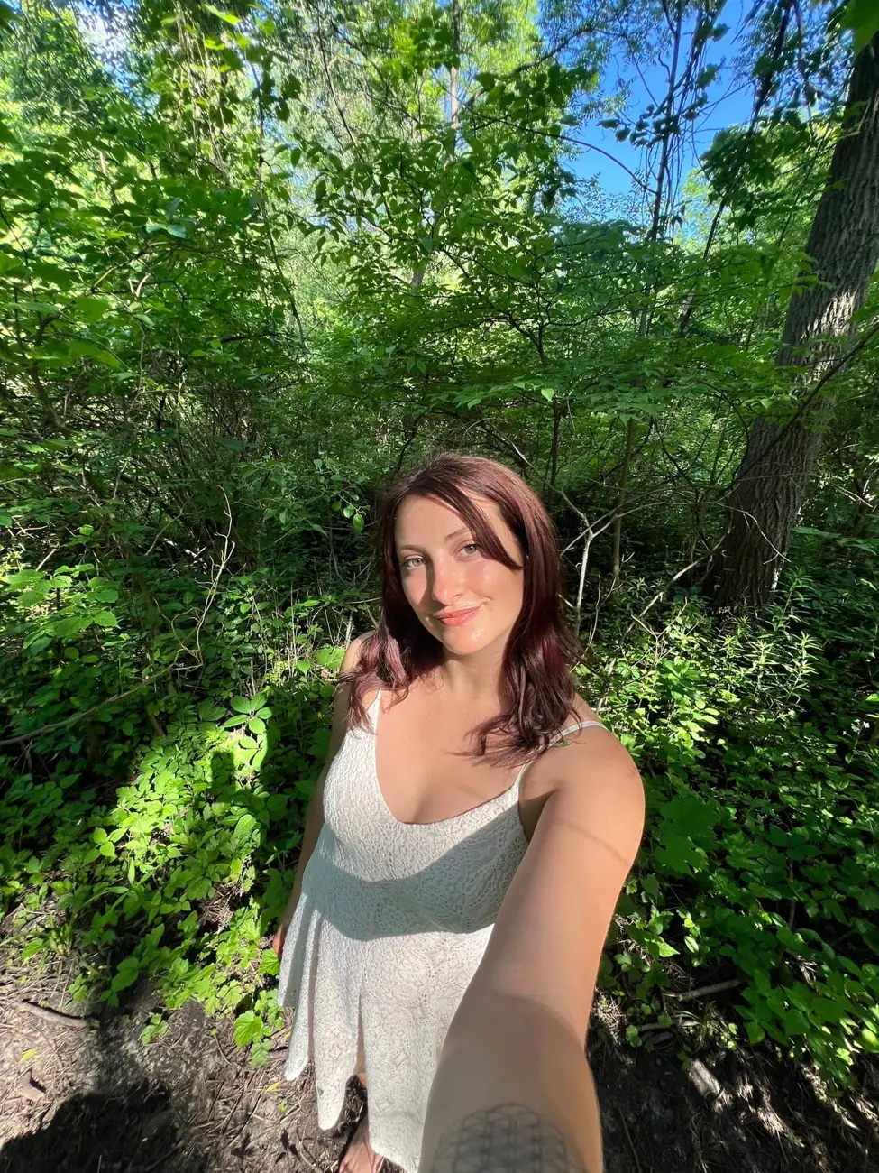 Kait outdoors among green trees